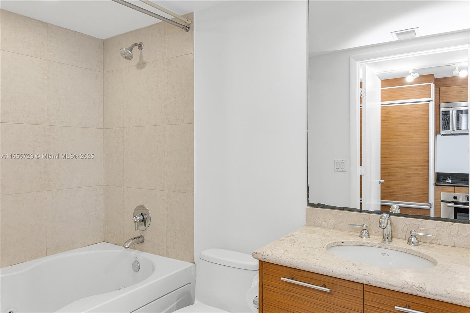 50 Biscayne Boulevard, Unit 4809 Miami, FL 33132 - Photo 7 of 11 a bathroom with a granite countertop sink a mirror and a bathtub