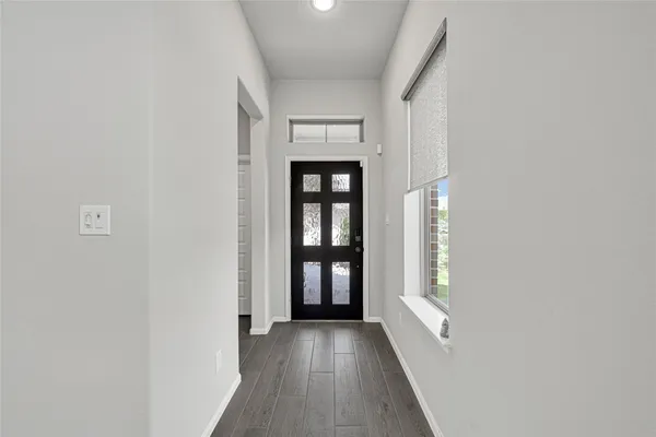a view of an empty room with window and wooden floor