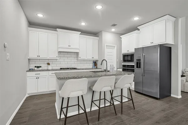 a kitchen with stainless steel appliances granite countertop a white cabinets and a refrigerator