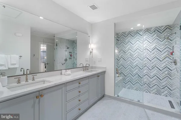 a bathroom with a granite countertop sink a mirror and shower