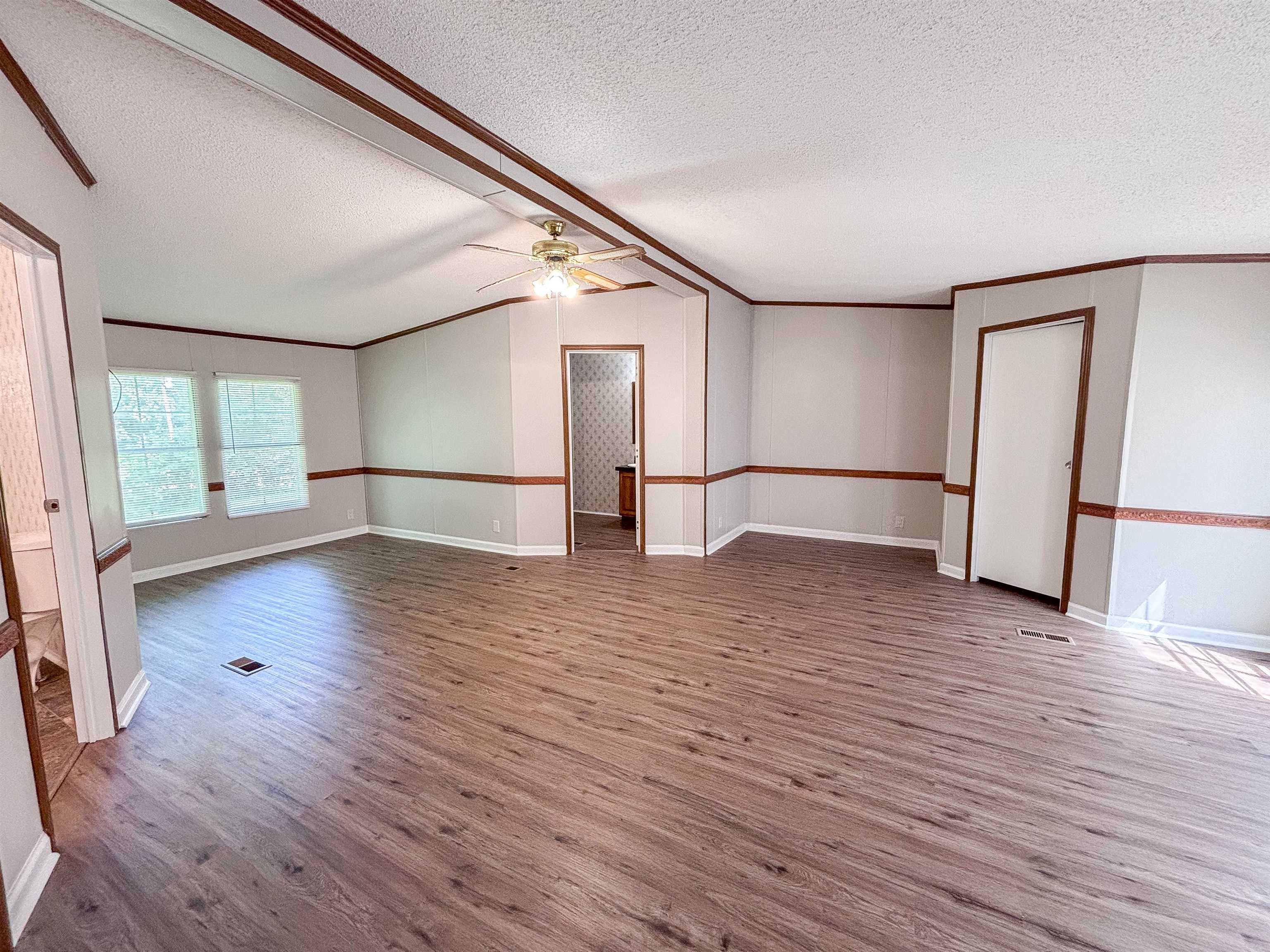 2847 Holly Grove Road Covington, TN 38019 - Photo 14 of 36 Spacious room featuring wood-finish flooring, light gray walls with chair rail molding, and multiple windows