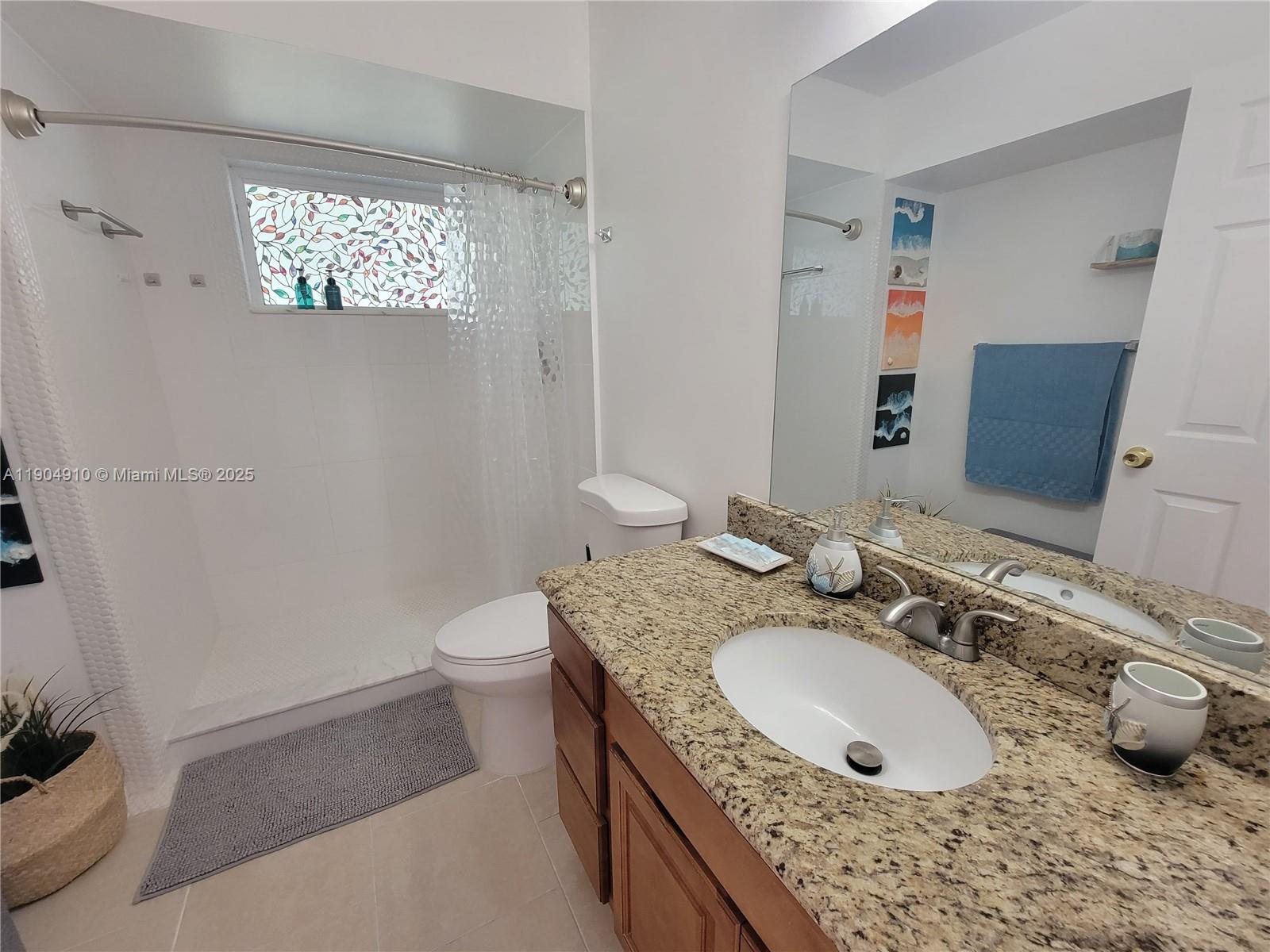 210 Banyan Drive Port St. Lucie, FL 34952 - Photo 14 of 22 a bathroom with a granite countertop sink a toilet and a mirror