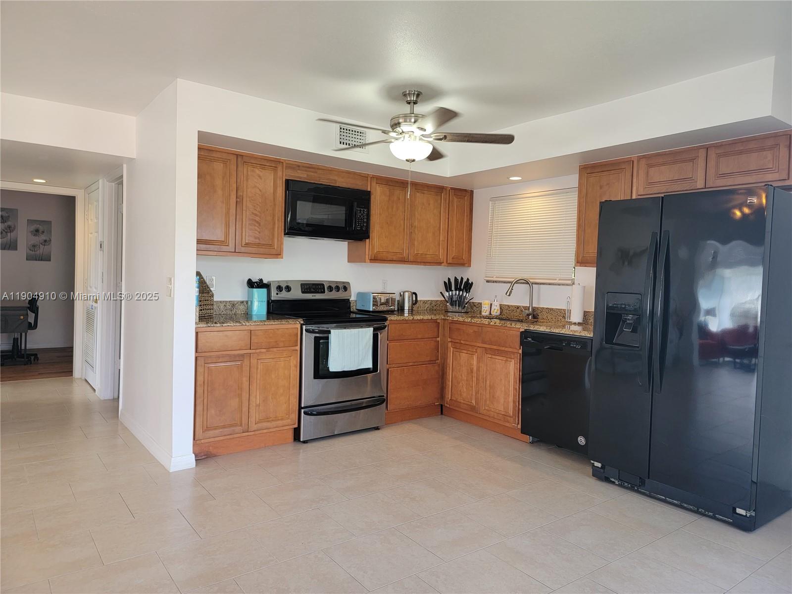 210 Banyan Drive Port St. Lucie, FL 34952 - Photo 7 of 22 a kitchen with stainless steel appliances kitchen island granite countertop a refrigerator a sink dishwasher a stove with white cabinets and wooden floor