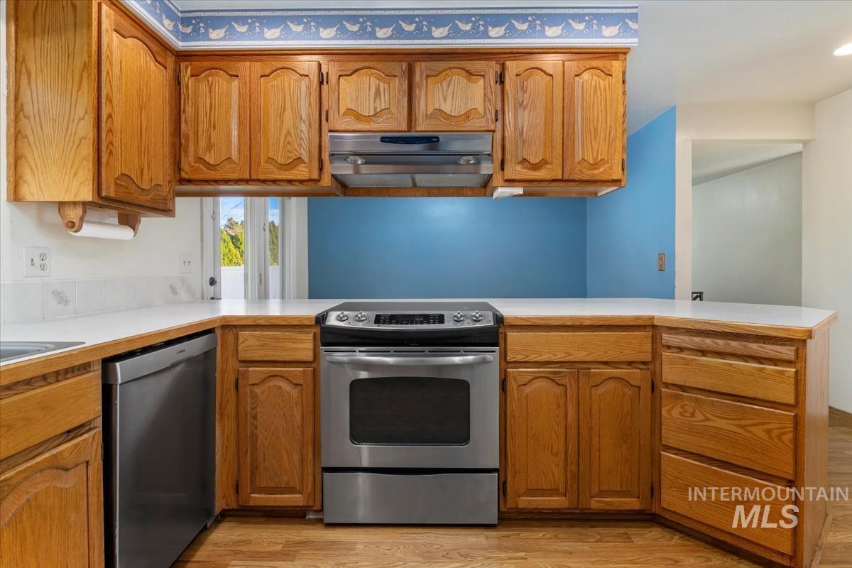 3850 Rugby Drive Boise, ID 83704 - Photo 13 of 44 Kitchen with a peninsula, stainless steel appliances, brown cabinetry, light countertops, and light wood finished floors