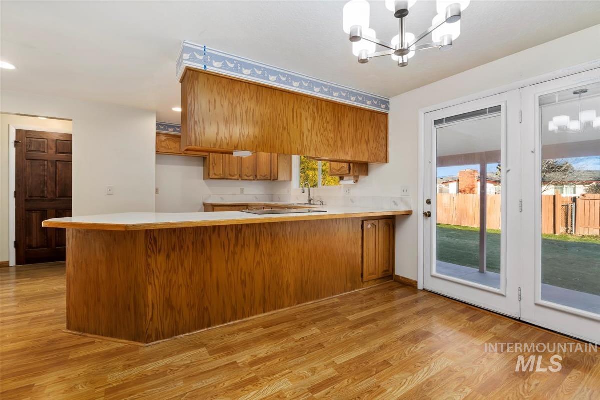 3850 Rugby Drive Boise, ID 83704 - Photo 16 of 44 Kitchen with brown cabinets, light countertops, a chandelier, a peninsula, and light wood-type flooring
