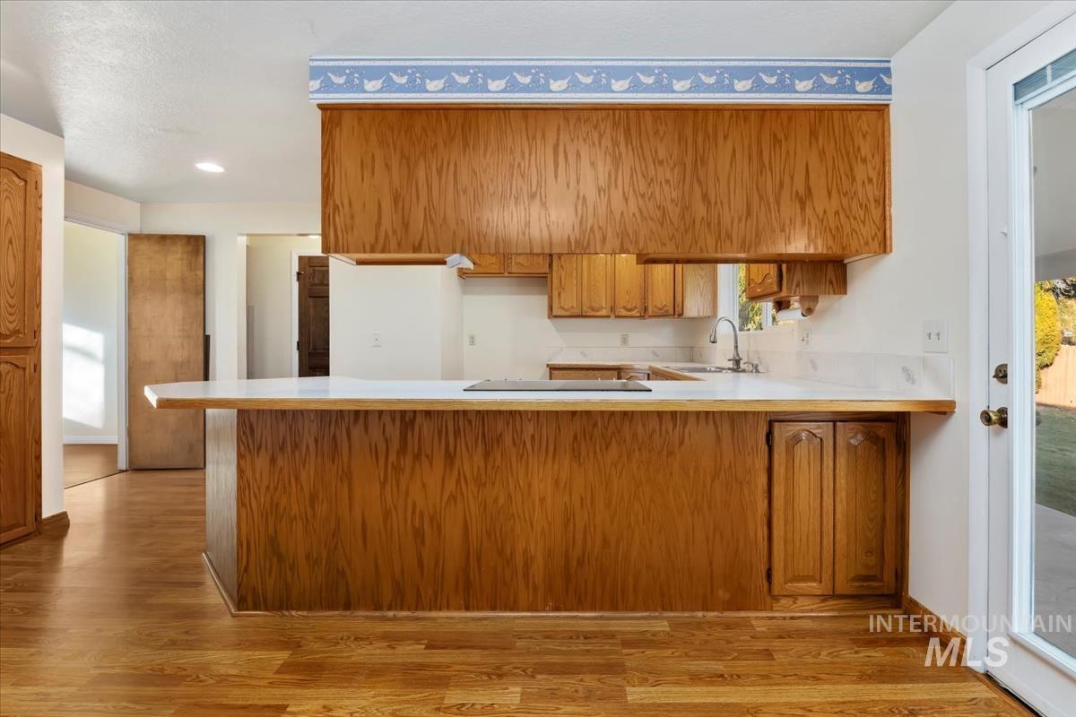 3850 Rugby Drive Boise, ID 83704 - Photo 17 of 44 Kitchen with brown cabinetry, light countertops, light wood-style floors, and a peninsula