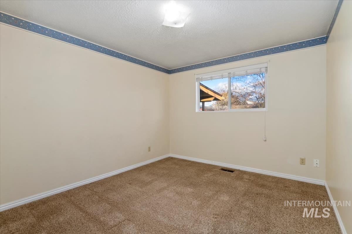 3850 Rugby Drive Boise, ID 83704 - Photo 18 of 44 Carpeted spare room featuring baseboards and a textured ceiling