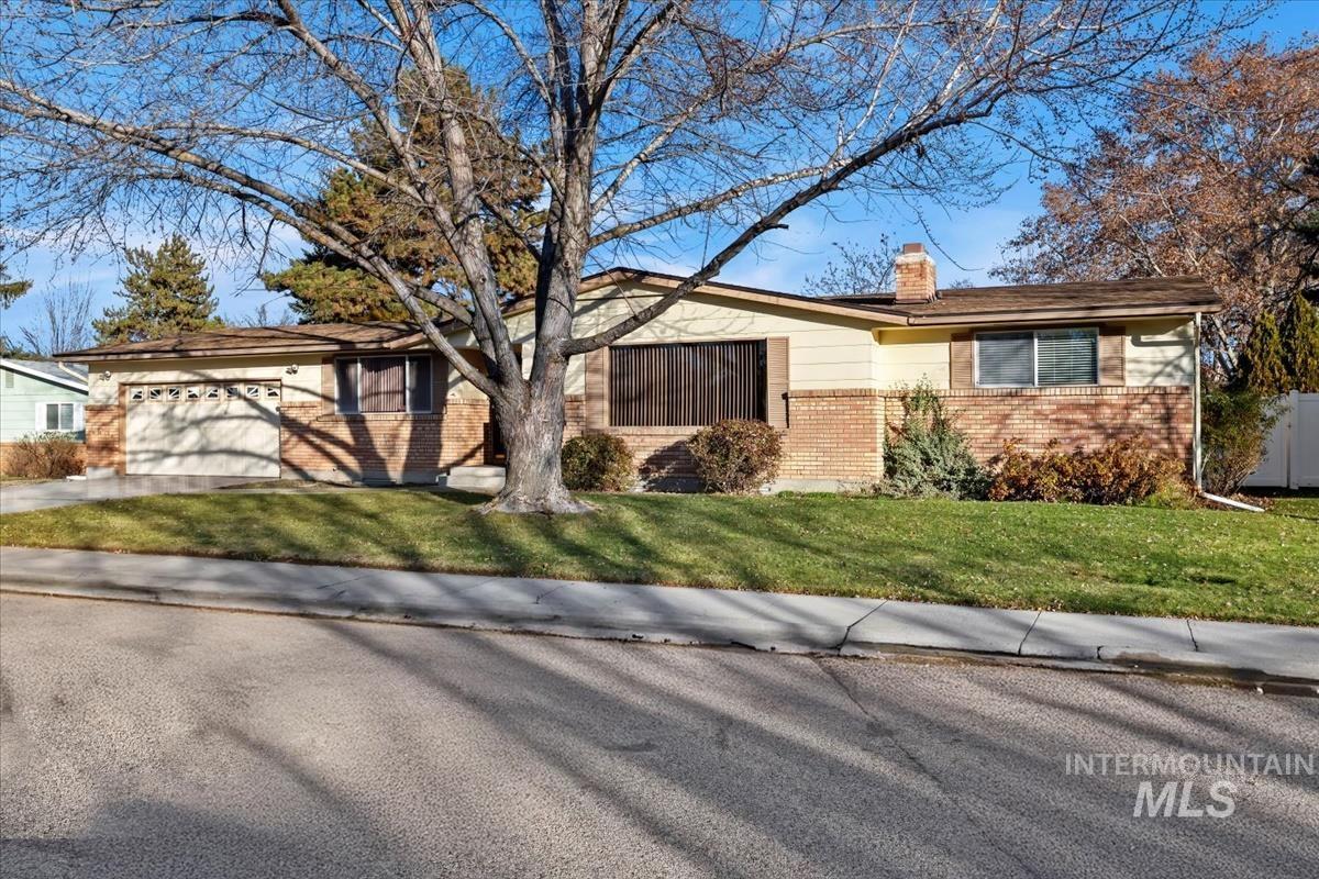 3850 Rugby Drive Boise, ID 83704 - Photo 2 of 44 View of front facade featuring a chimney, a front lawn, brick siding, concrete driveway, and an attached garage.