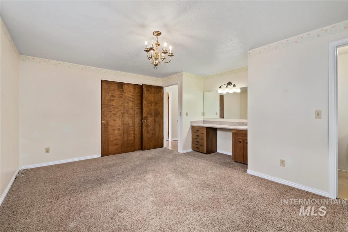 3850 Rugby Drive Boise, ID 83704 - Photo 25 of 44 Unfurnished bedroom with light colored carpet, a closet, a chandelier, and a desk