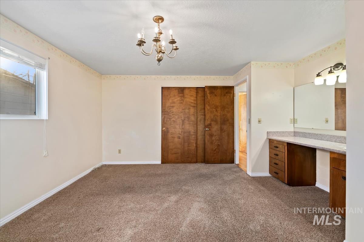 3850 Rugby Drive Boise, ID 83704 - Photo 27 of 44 Unfurnished bedroom with a closet, a chandelier, dark colored carpet, and a desk