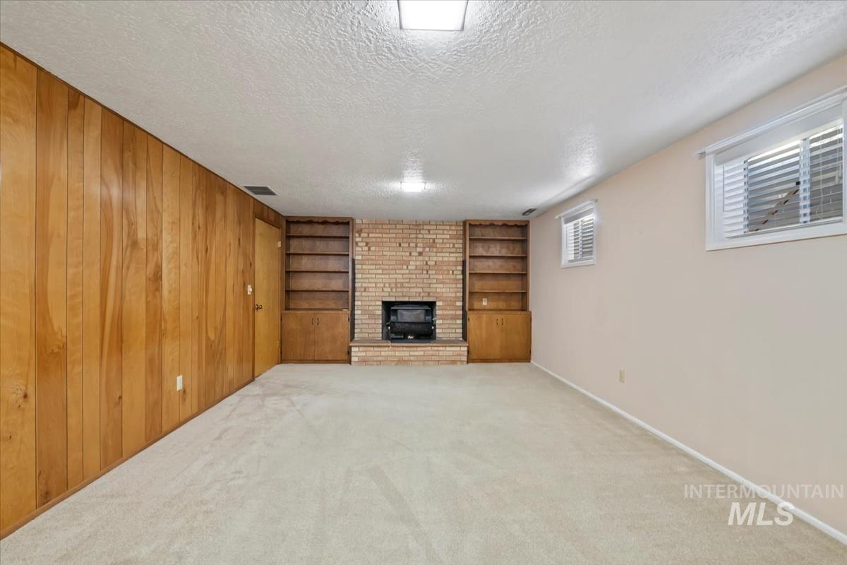 3850 Rugby Drive Boise, ID 83704 - Photo 32 of 44 Unfurnished living room featuring built in shelves, a textured ceiling, a fireplace, and carpet flooring