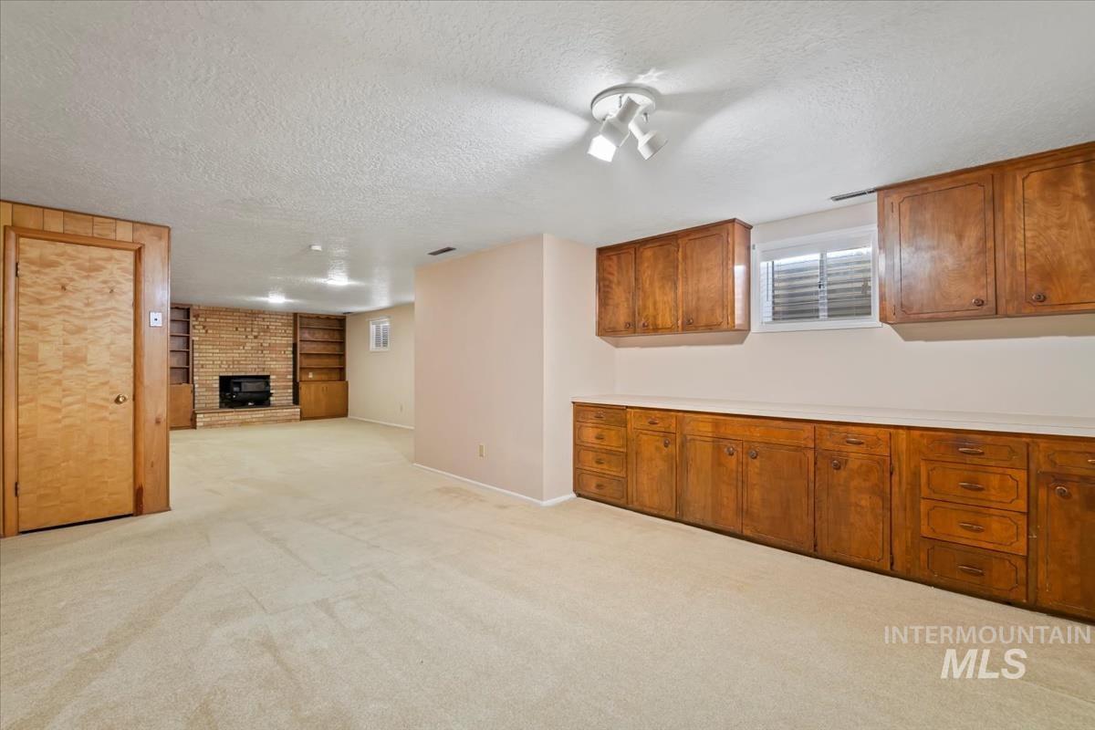 3850 Rugby Drive Boise, ID 83704 - Photo 34 of 44 Kitchen with light countertops, brown cabinets, light colored carpet, a fireplace, and a textured ceiling