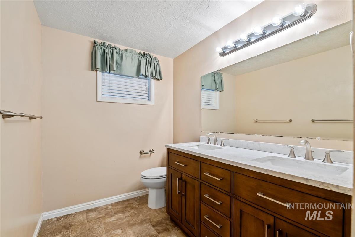 3850 Rugby Drive Boise, ID 83704 - Photo 37 of 44 Bathroom featuring double vanity, a textured ceiling, and stone finish flooring