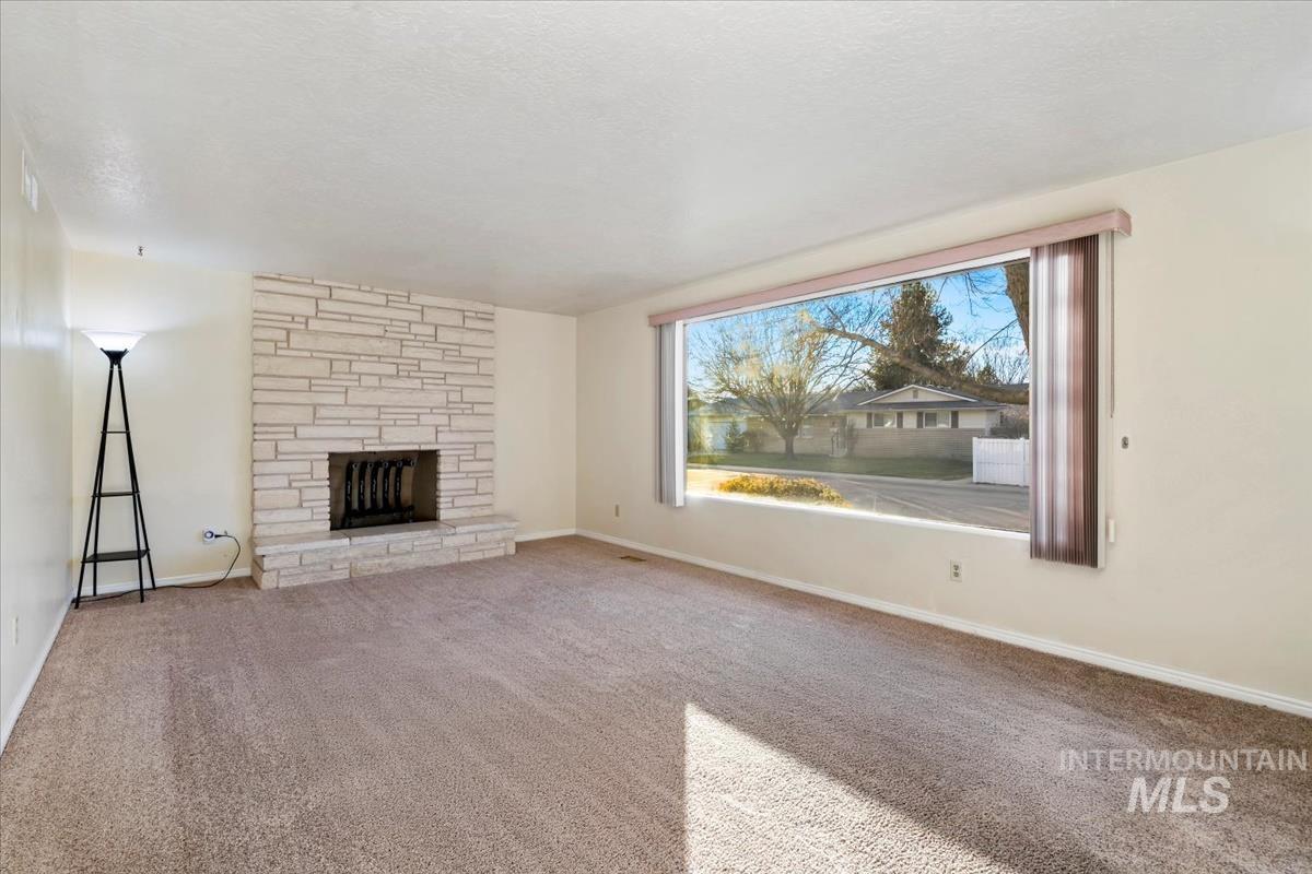3850 Rugby Drive Boise, ID 83704 - Photo 5 of 44 Unfurnished living room featuring a stone fireplace, carpet, and a textured ceiling