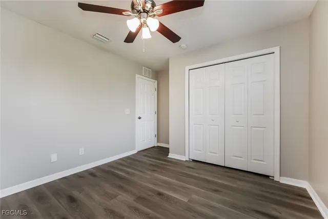 an empty room with wooden floor closet and fan