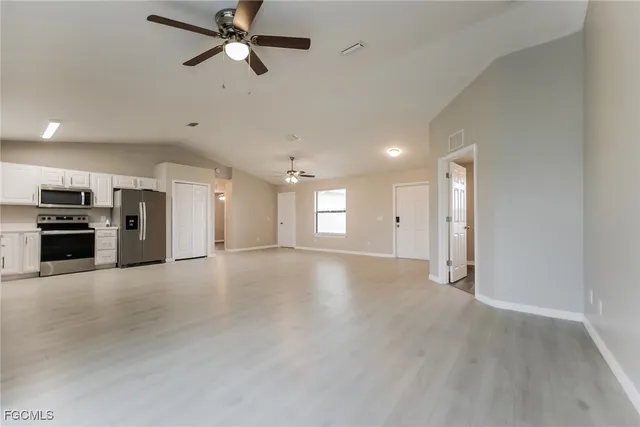 an empty room with a kitchen and a fireplace