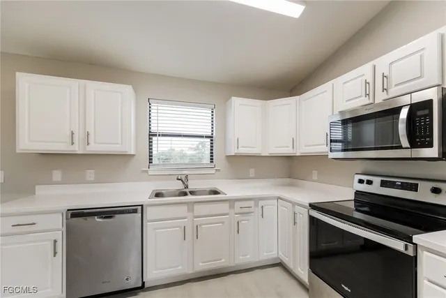a kitchen with white cabinets white stainless steel appliances and sink