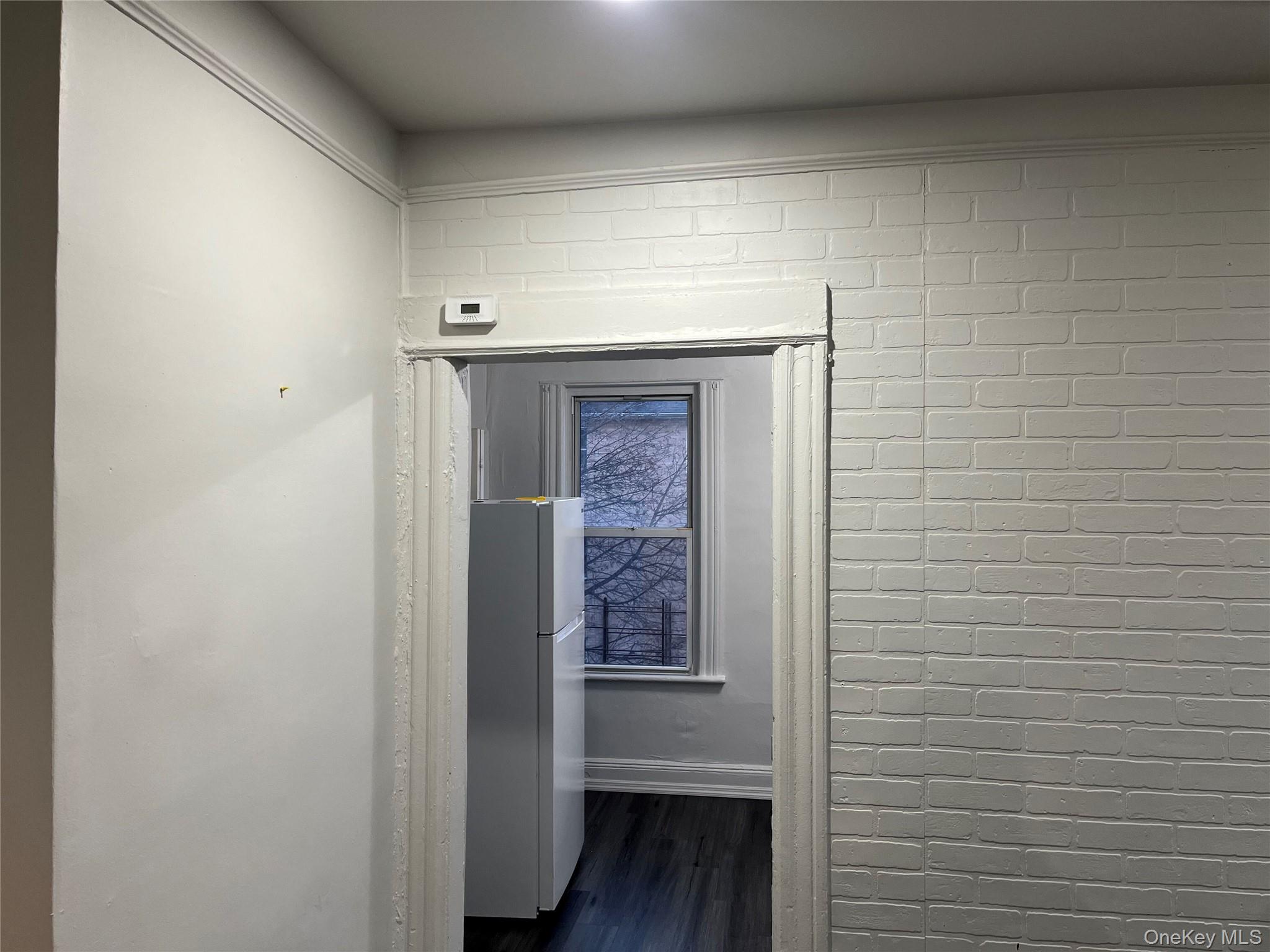 95-29 112th Street, Unit 2 Queens, NY 11419 - Photo 8 of 10 Detailed view of freestanding refrigerator, wood finished floors, and brick wall
