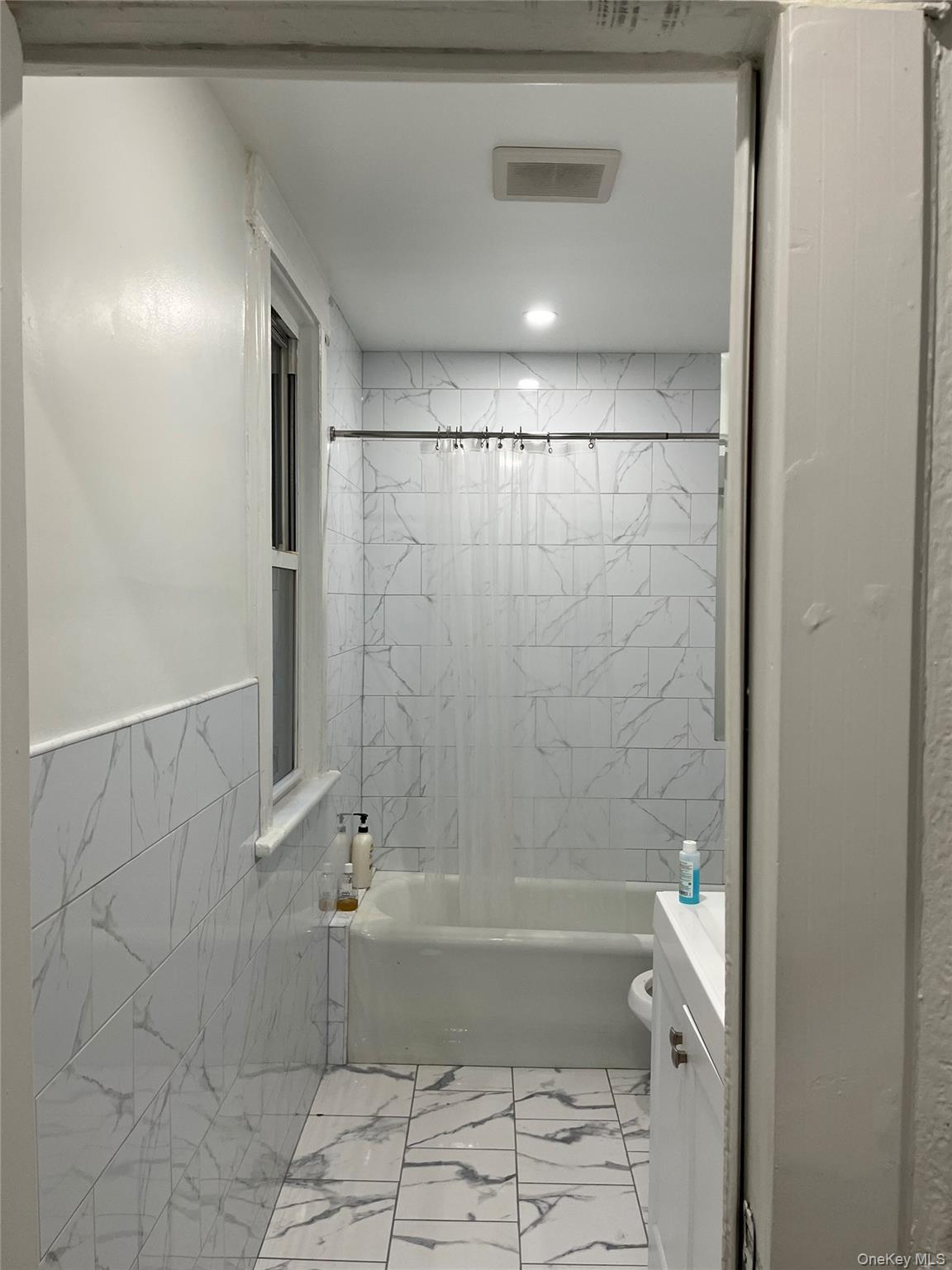 95-29 112th Street, Unit 2 Queens, NY 11419 - Photo 9 of 10 Bathroom featuring shower / bathtub combination with curtain, light marble finish floors, vanity, and tile walls
