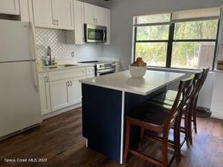 a kitchen with stainless steel appliances granite countertop a table chairs sink and cabinets