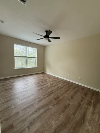an empty room with wooden floor and windows