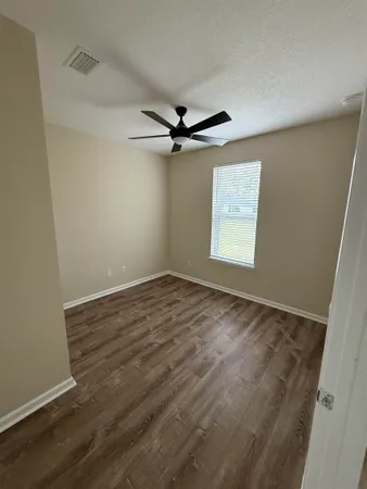 an empty room with a window and a ceiling fan
