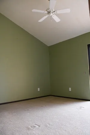 an empty room with a ceiling fan and a window