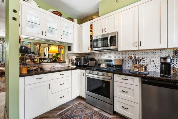 a kitchen with stainless steel appliances granite countertop white cabinets a sink and dishwasher
