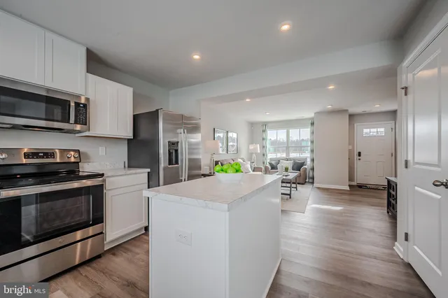 a kitchen with stainless steel appliances kitchen island granite countertop a stove a sink a refrigerator a microwave oven with cabinets and wooden floor