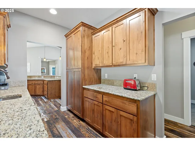 a kitchen with stainless steel appliances kitchen island granite countertop a table chairs and a refrigerator