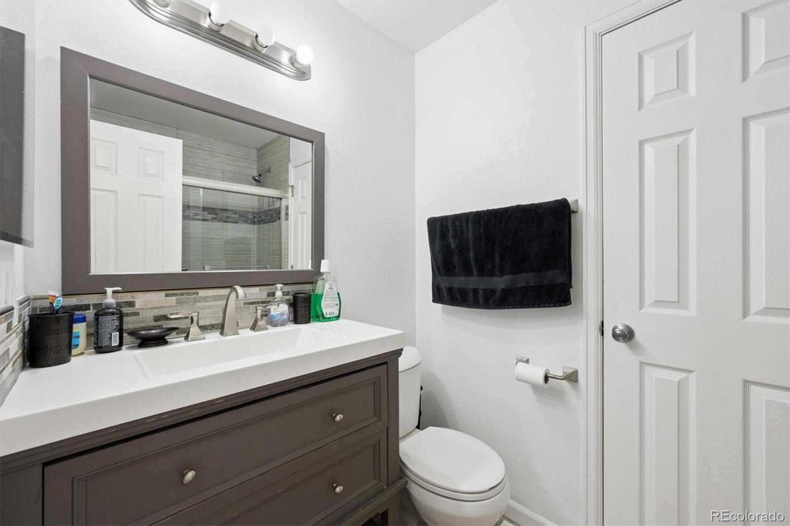 11688 East Cedar Avenue Aurora, CO 80012 - Photo 14 of 24 a bathroom with a toilet a sink a mirror a shower and a window