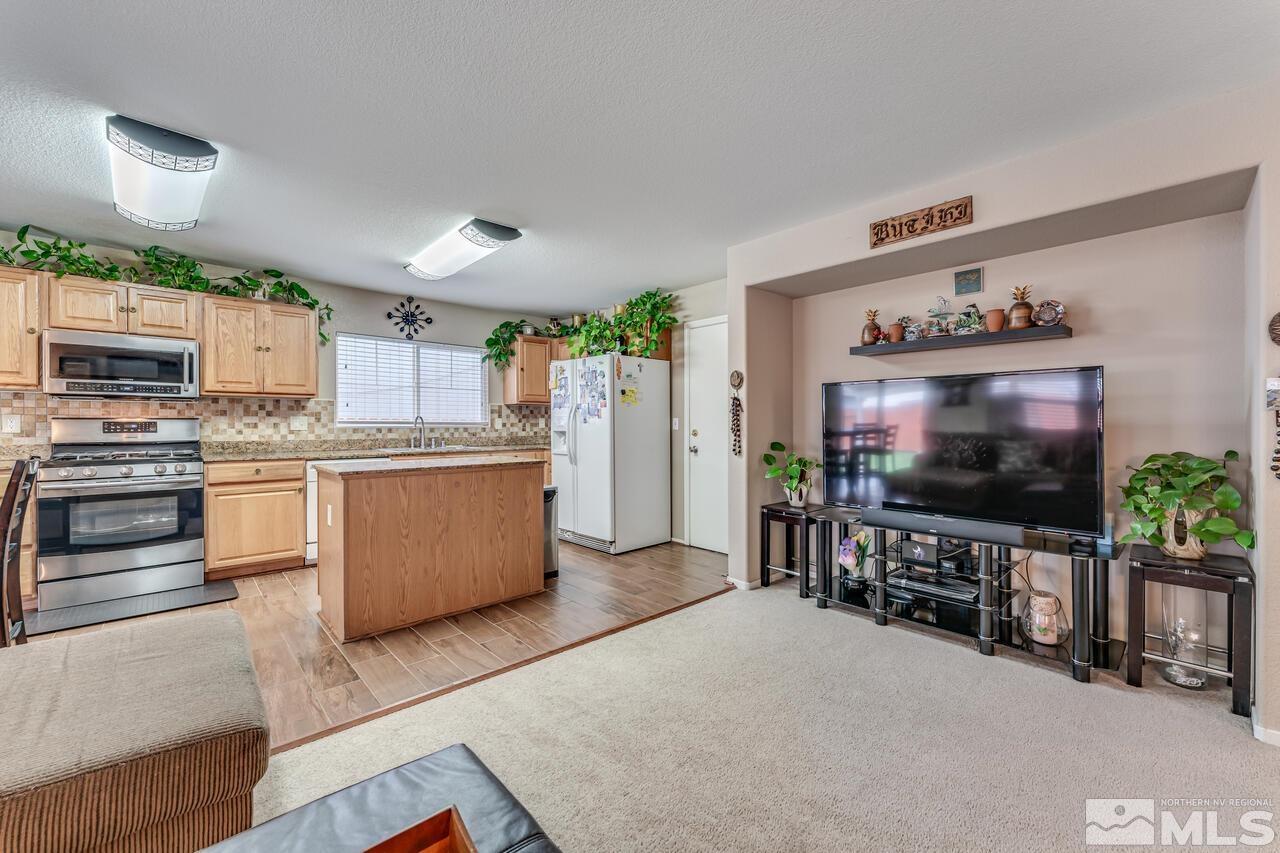7699 Corso Street Reno, NV 89506 - Photo 13 of 36 a kitchen with stainless steel appliances a stove a microwave a sink and a refrigerator