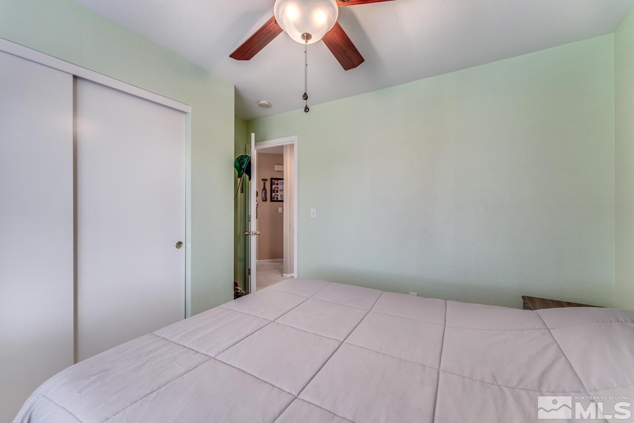 7699 Corso Street Reno, NV 89506 - Photo 23 of 36 a bedroom with a bed and a chandelier fan