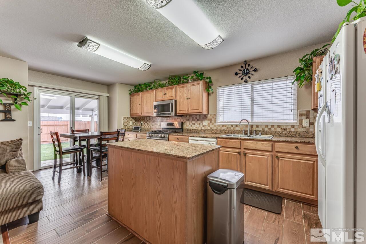 7699 Corso Street Reno, NV 89506 - Photo 9 of 36 a kitchen with granite countertop a sink appliances cabinets and dining table