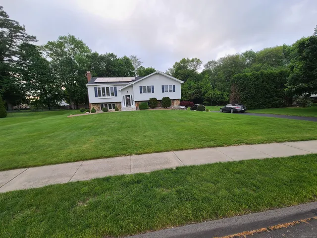a view of a house with a big yard and large trees
