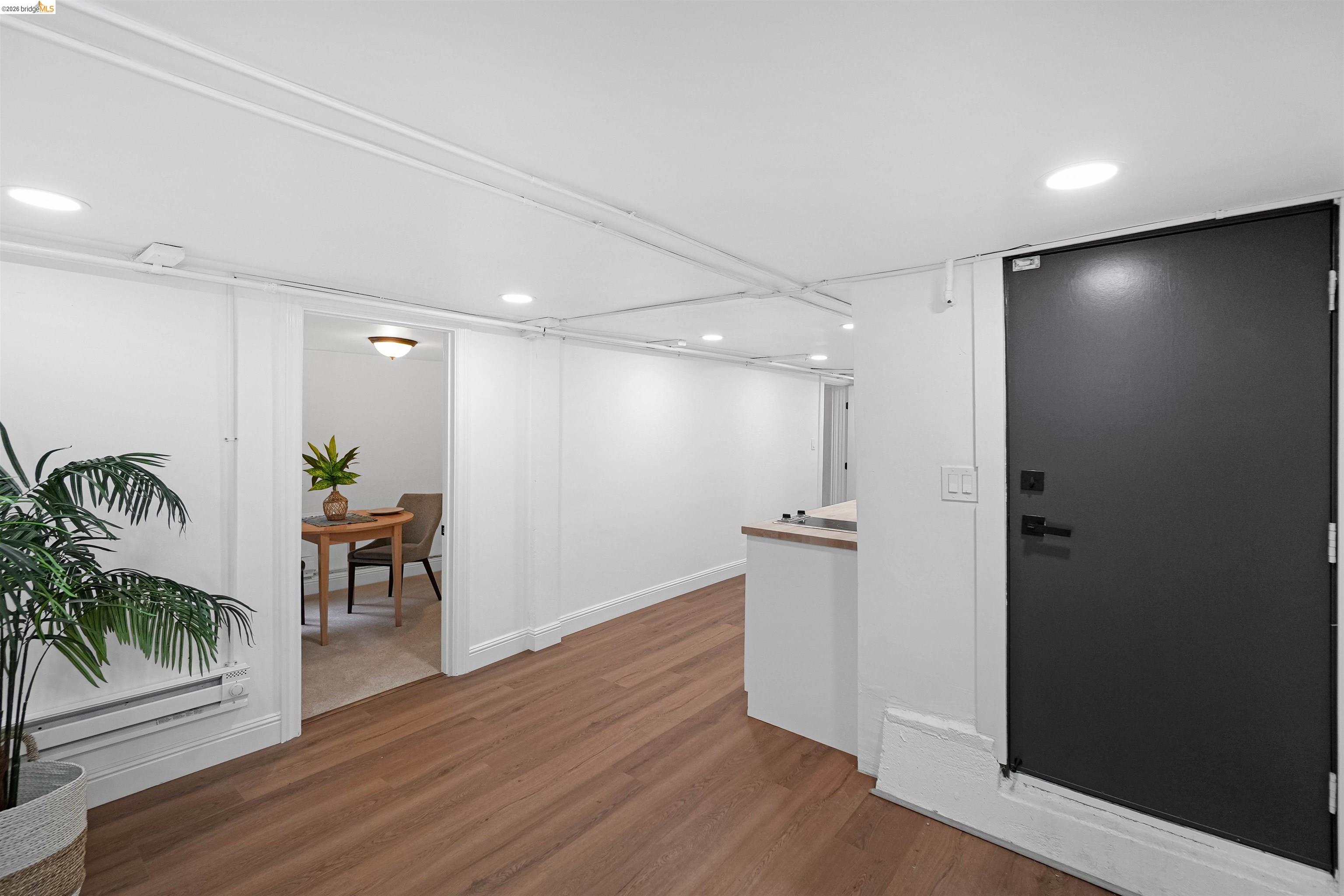 1812 Woolsey Street Berkeley, CA 94703 - Photo 33 of 48 Interior hallway featuring wood-finish flooring, recessed lighting, white walls, and a black solid door with contemporary hardware
