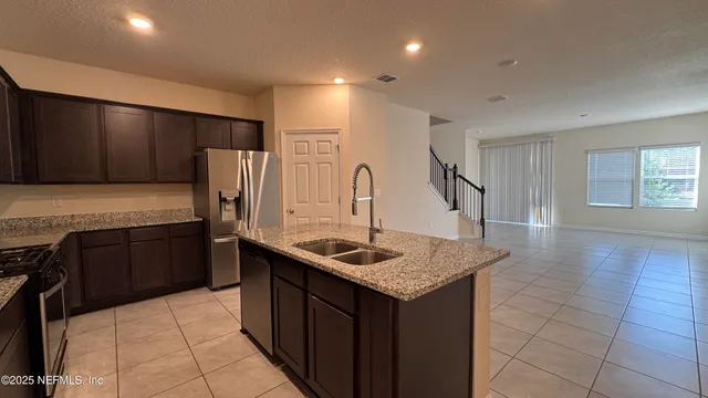 a kitchen with kitchen island granite countertop a sink stove and refrigerator