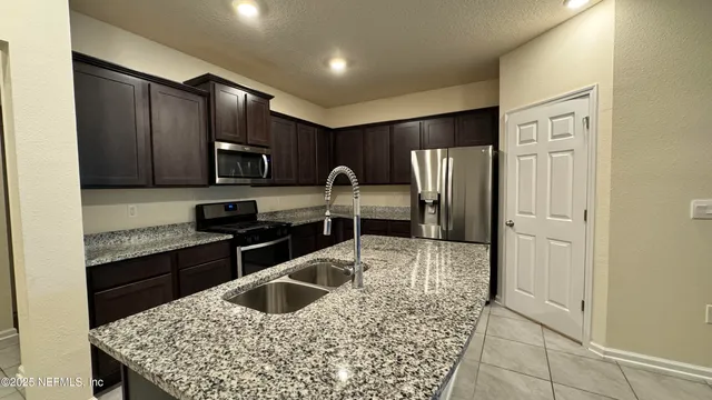 a kitchen with stainless steel appliances granite countertop a refrigerator sink and stove