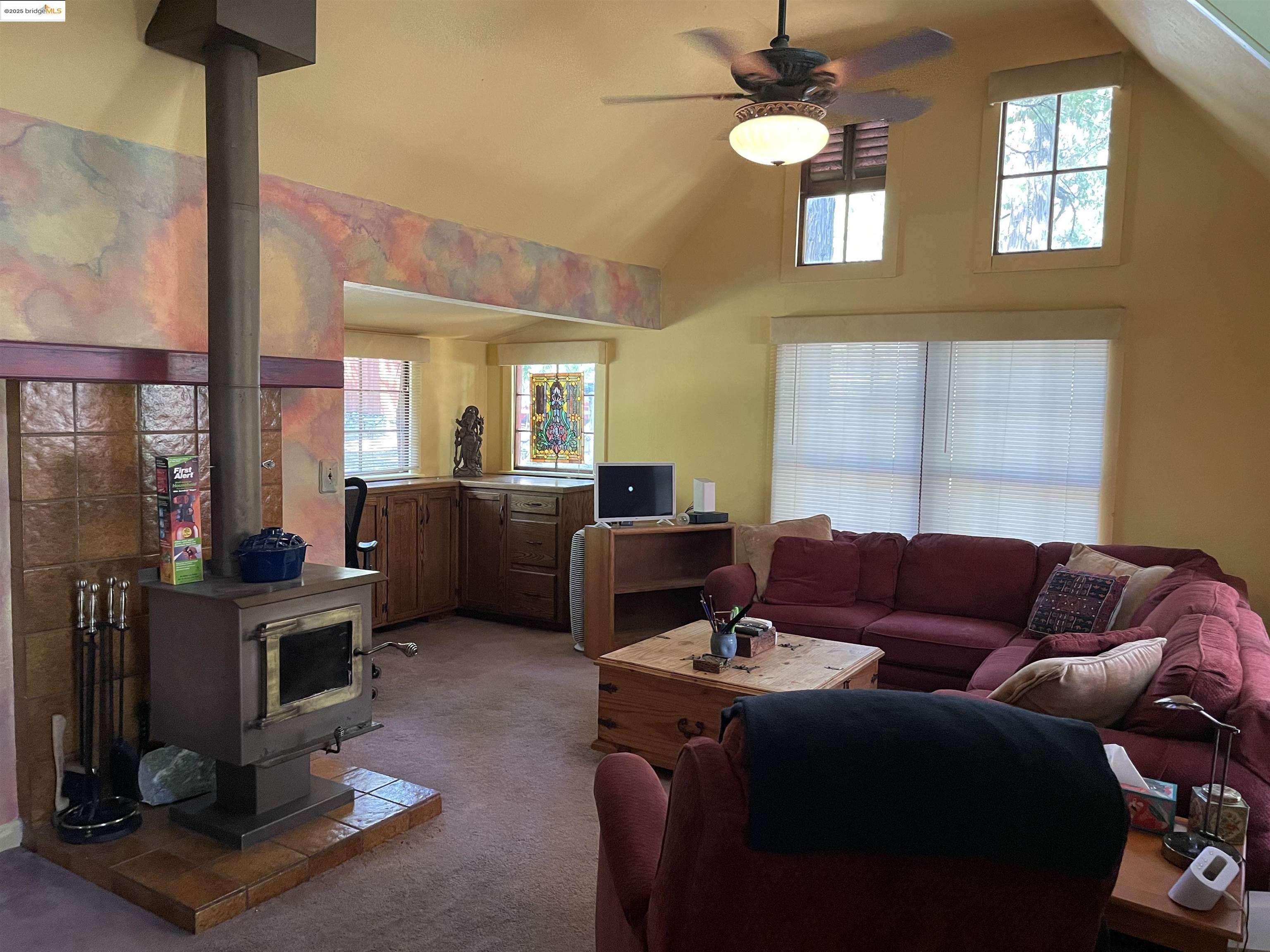 22846 Fuller Road Twain Harte, CA 95383 - Photo 4 of 40 Carpeted living area featuring a wood stove, high vaulted ceiling, and ceiling fan