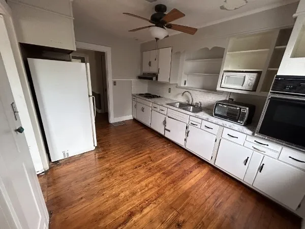 a kitchen with stainless steel appliances a refrigerator a sink a stove and white cabinets