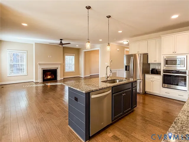 a kitchen with stainless steel appliances granite countertop a stove a refrigerator and a fireplace