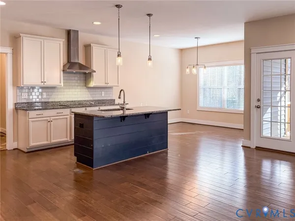 a kitchen with stainless steel appliances granite countertop a sink a stove and a wooden floors