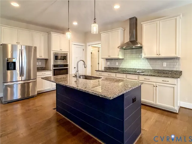a kitchen with stainless steel appliances granite countertop a sink a stove and a refrigerator