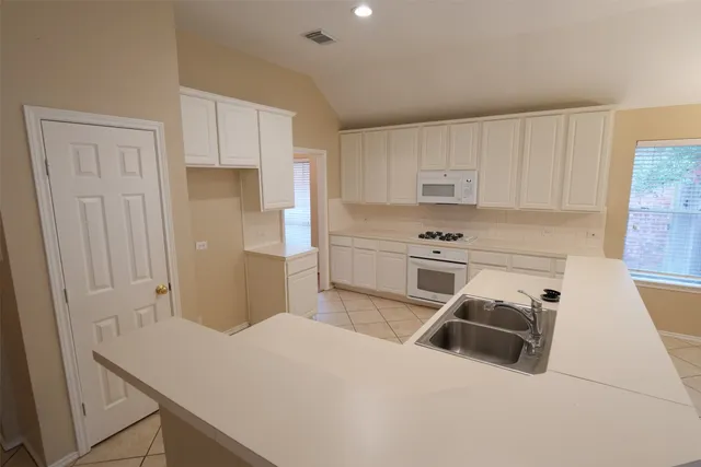 a kitchen with stainless steel appliances a stove a sink and white cabinets