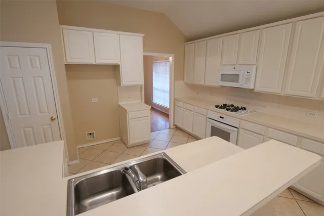 a kitchen with white cabinets and appliances