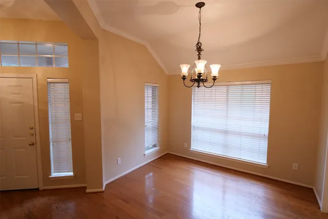 a view of a room with wooden floor chandelier and windows