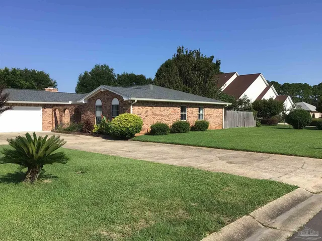 a view of a house with a big yard plants and large trees