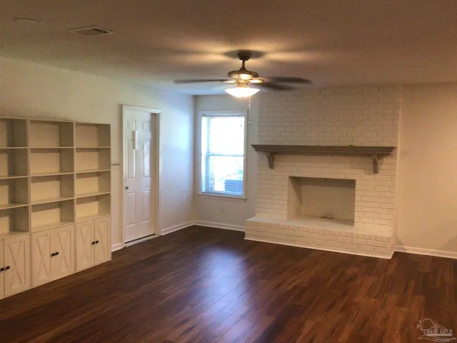 an empty room with wooden floor chandelier fan and windows