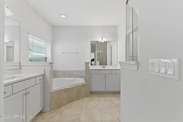 a bathroom with a granite countertop bathtub shower sink vanity and toilet