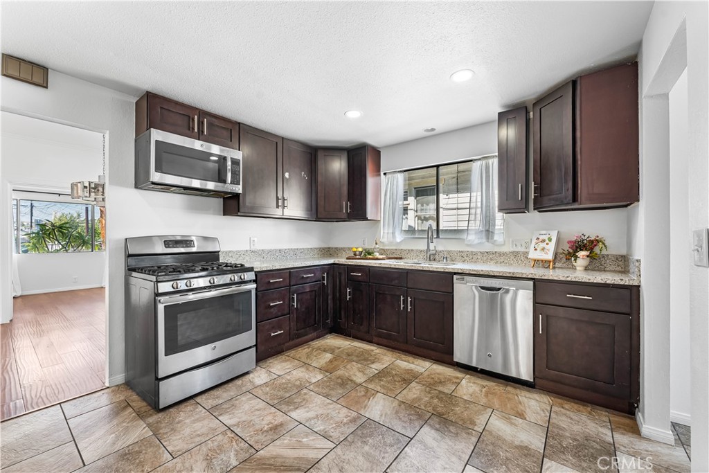 1178 Spence Street Los Angeles, CA 90023 - Photo 10 of 36 a kitchen with stainless steel appliances granite countertop a stove sink microwave and refrigerator